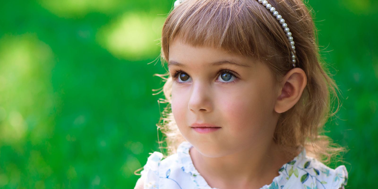 A young girl with bright eyes and a pearl headband, gazing thoughtfully | Source: Shutterstock