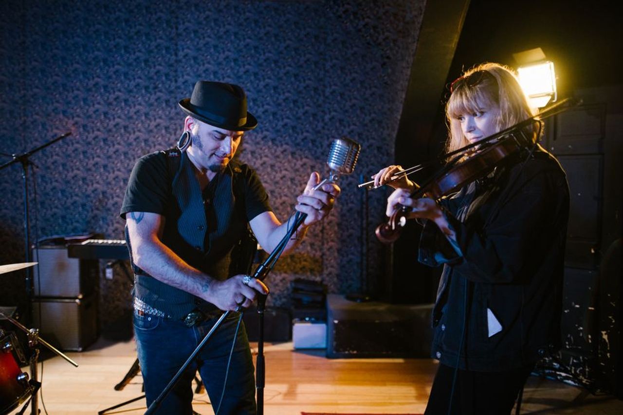 Man with microphone and woman violinist in a music studio performance.