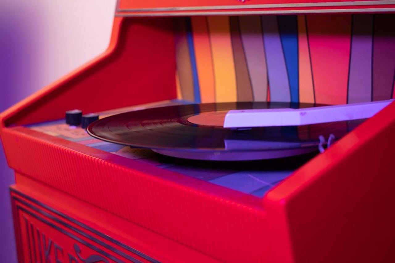 Close-up of a vibrant red jukebox playing a vinyl record, exuding retro vibes.