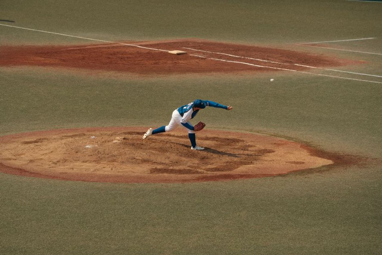A skilled baseball pitcher delivers a pitch on a sunlit field in Tokyo, Japan. Captured in dynamic motion.
