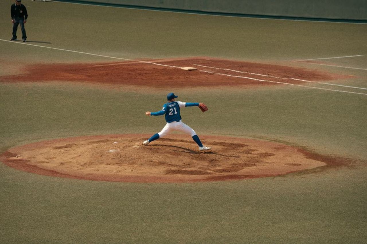 Baseball player mid-throw during a game at a Tokyo baseball field. Capturing the intensity and focus of sports.
