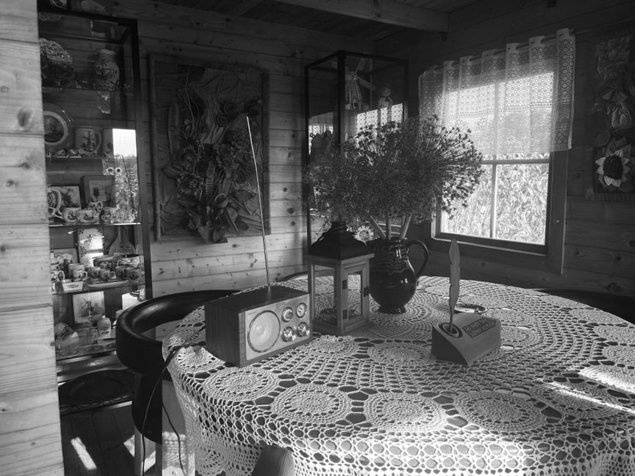 Cozy vintage interior with lace tablecloth, radio, and floral decor by the window.