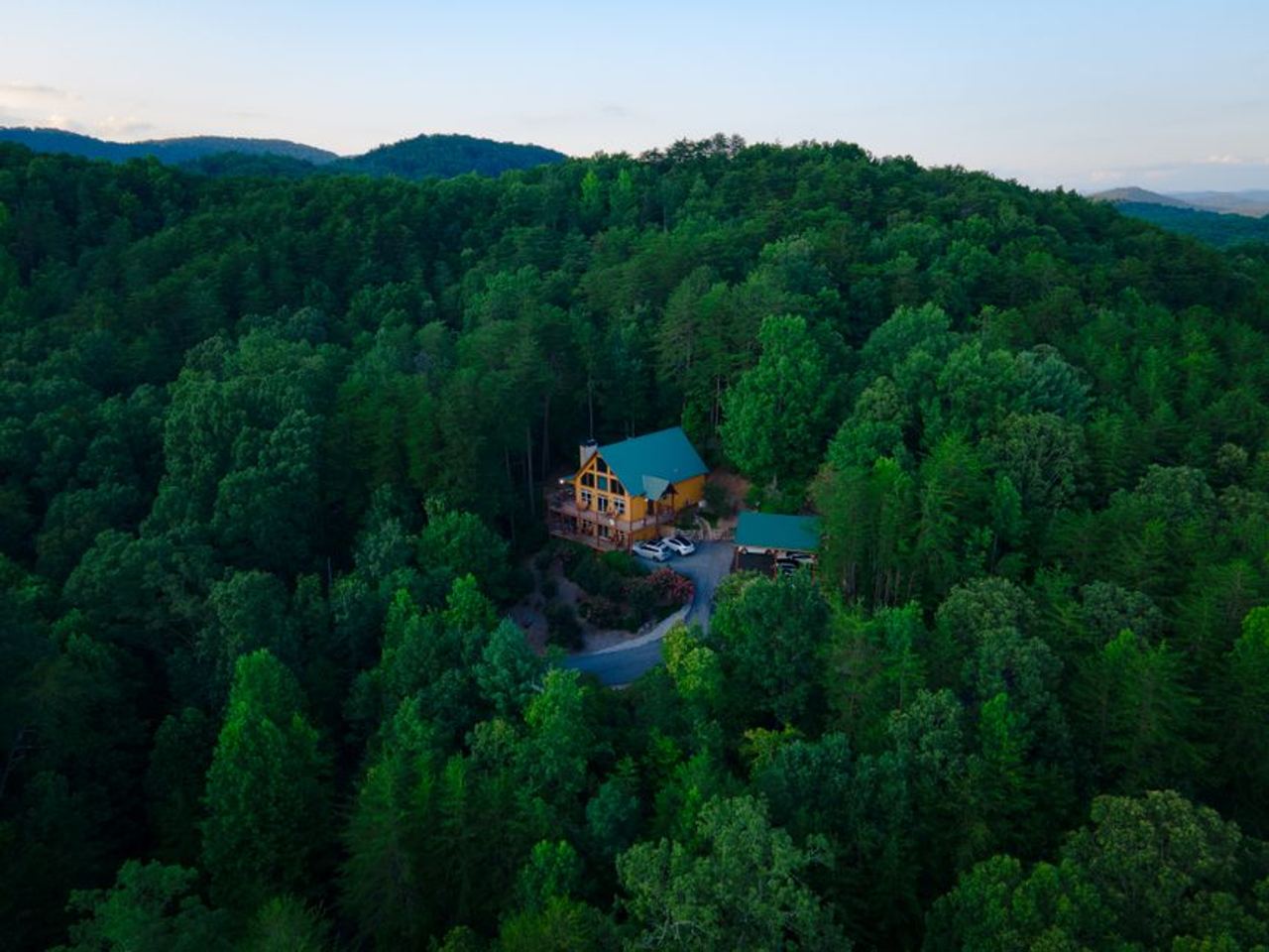 A serene aerial view of a cabin nestled within dense green forests, showcasing nature's tranquility in Cleveland, Georgia.