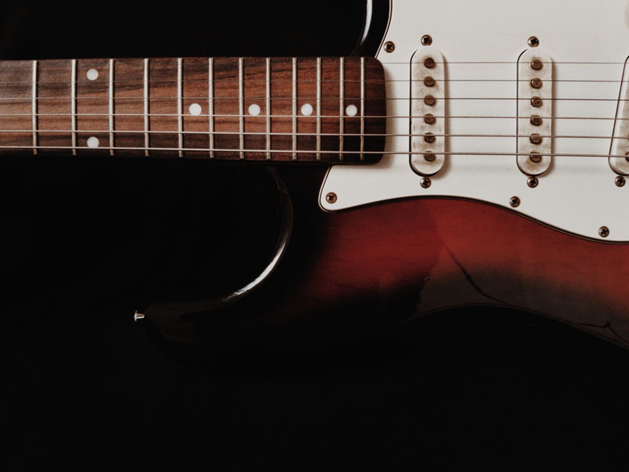 Detailed shot of an electric guitar with a dark background emphasizing the instrument's features.