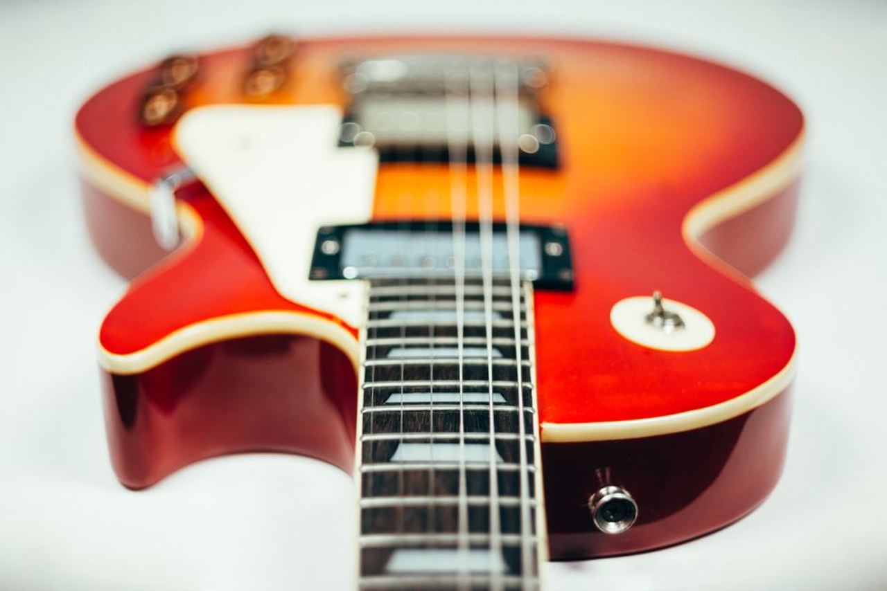 Detailed close-up image of an electric guitar showcasing its neck and body in vibrant hues.