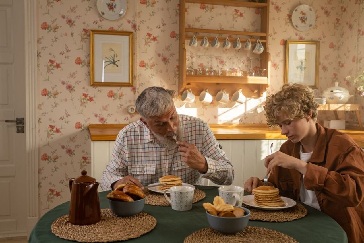 Father and son sharing a cozy breakfast of pancakes in a vintage kitchen setting.